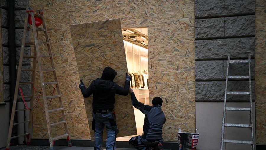 Para pekerja mengamankan toko Brunello Cucinelli dengan papan kayu menjelang aksi protes yang diperkirakan akan dilakukan oleh gerakan pemuda