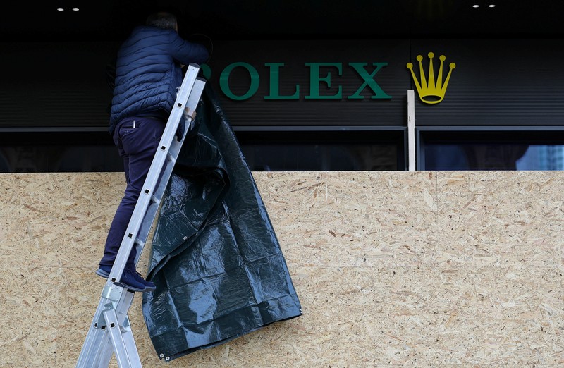 Para pekerja memasang papan kayu untuk mengamankan toko Bvlgari menjelang aksi protes yang diperkirakan akan dilakukan oleh gerakan pemuda